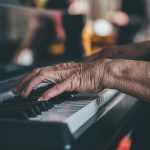 oude handen op een piano